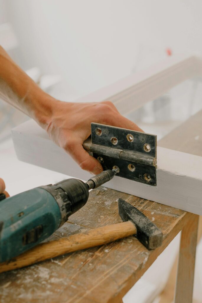 drill installing screw into door with hammer on table